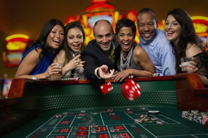 Excited friends gambling at craps table in casino